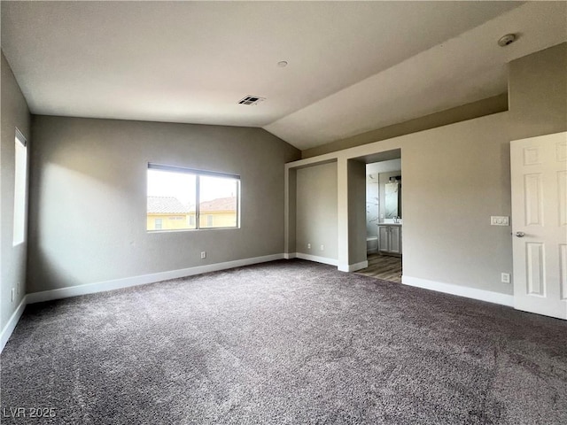 carpeted spare room featuring visible vents, baseboards, and vaulted ceiling