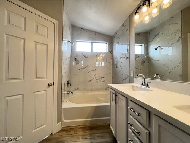 bathroom with lofted ceiling, wood finished floors, double vanity, and a sink