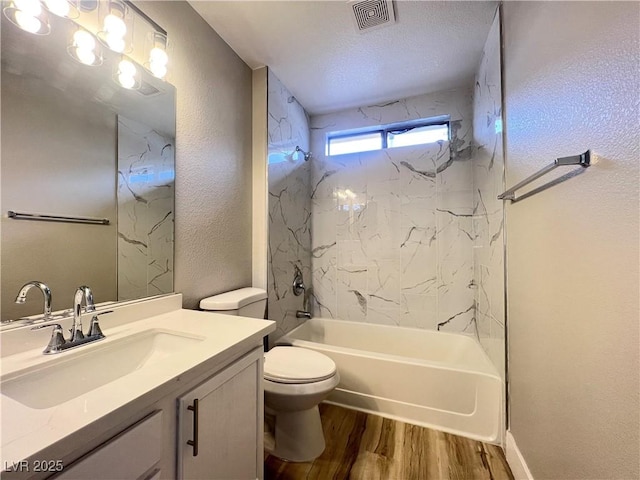 full bathroom with visible vents, shower / washtub combination, toilet, wood finished floors, and vanity