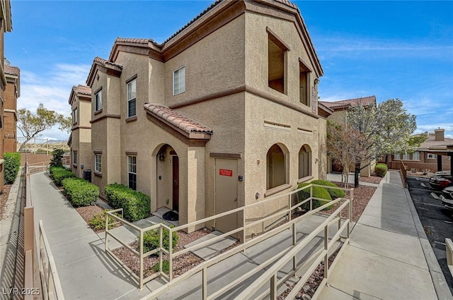 view of front of house with stucco siding, a tile roof, and fence