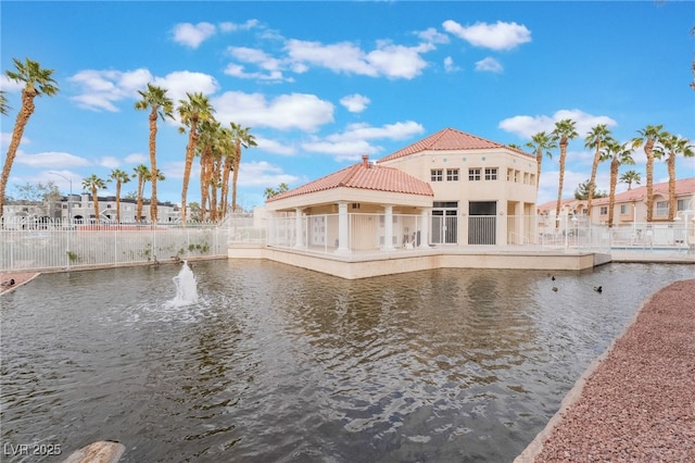 back of property featuring stucco siding, a water view, and a tile roof