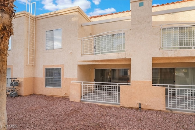 rear view of house with stucco siding and a balcony