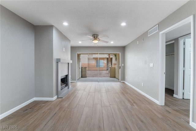 unfurnished living room featuring wood finished floors, a fireplace, visible vents, and baseboards