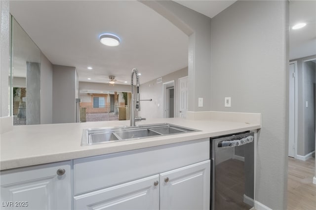 kitchen with dishwasher, light countertops, white cabinets, and a sink