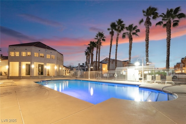 pool at dusk with a patio, a community pool, and fence