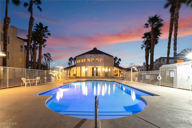 pool at dusk featuring a community pool, a patio, and fence