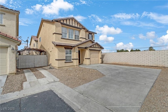 view of front of property featuring fence, concrete driveway, stucco siding, an attached garage, and a gate