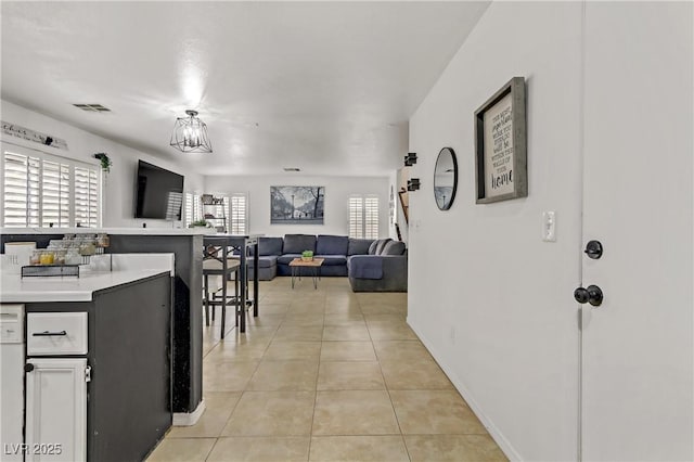 kitchen featuring visible vents, open floor plan, a breakfast bar area, light countertops, and light tile patterned flooring