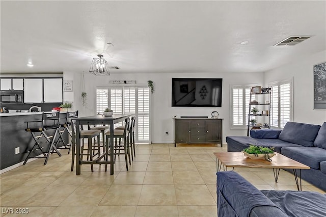 living area featuring light tile patterned flooring, visible vents, and a chandelier