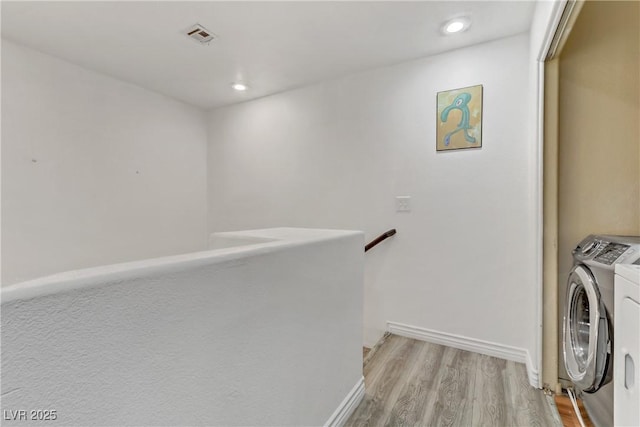 clothes washing area featuring visible vents, baseboards, laundry area, washer and dryer, and light wood-type flooring