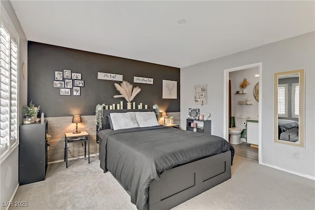 bedroom featuring an accent wall, carpet flooring, baseboards, and ensuite bathroom