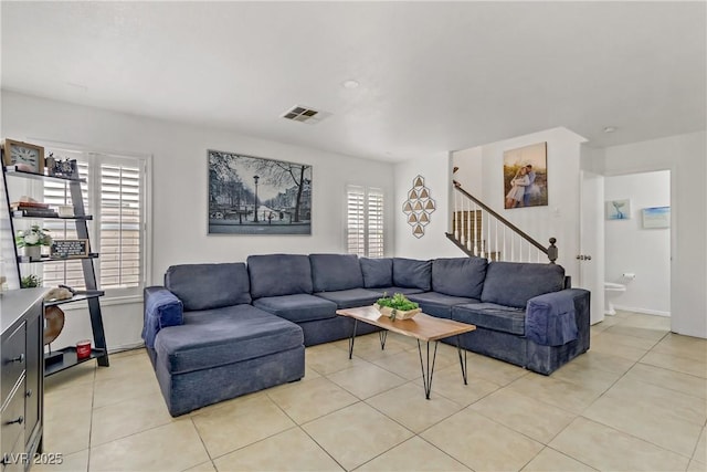 living room with light tile patterned floors, visible vents, and stairs