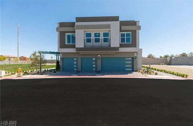 contemporary home with decorative driveway, an attached garage, and stucco siding