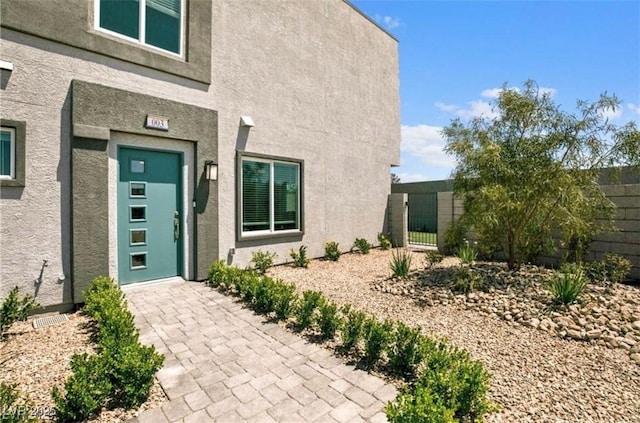 property entrance with stucco siding and fence