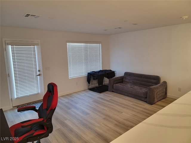 living area featuring baseboards, visible vents, and light wood-type flooring