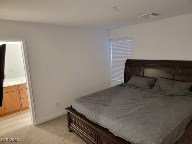 bedroom featuring visible vents, light carpet, baseboards, and ensuite bathroom