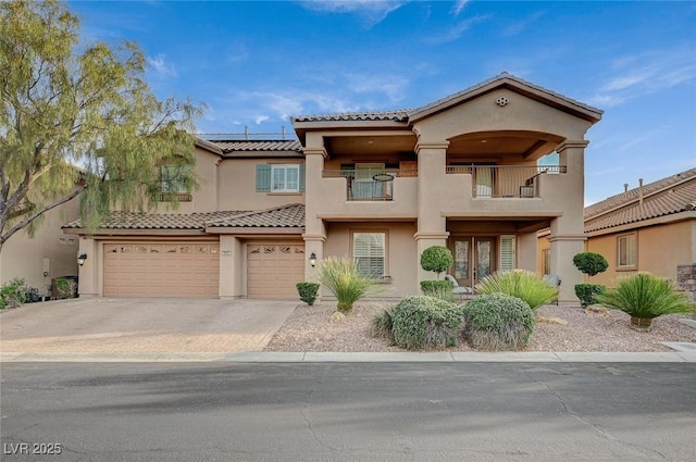 mediterranean / spanish-style home with solar panels, stucco siding, driveway, a balcony, and an attached garage