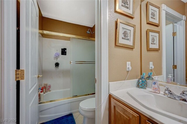 bathroom featuring tile patterned floors, toilet, vanity, and shower / bath combination with glass door