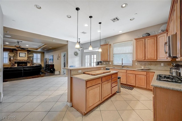 kitchen with light tile patterned floors, visible vents, a stone fireplace, and open floor plan