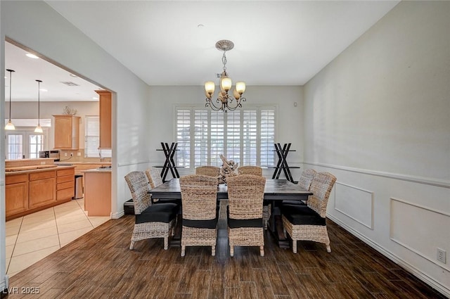 dining room with a chandelier, visible vents, wainscoting, and light wood-type flooring