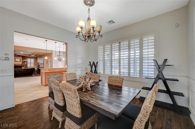 dining room featuring wood finished floors, visible vents, and a chandelier