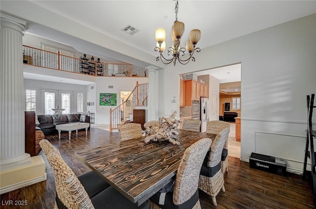 dining space with an inviting chandelier, decorative columns, dark wood-style floors, and visible vents