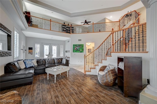 living area with a towering ceiling, french doors, wood finished floors, and stairs