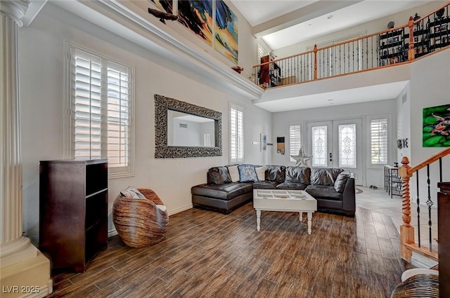 living area featuring stairway, decorative columns, wood finished floors, and french doors