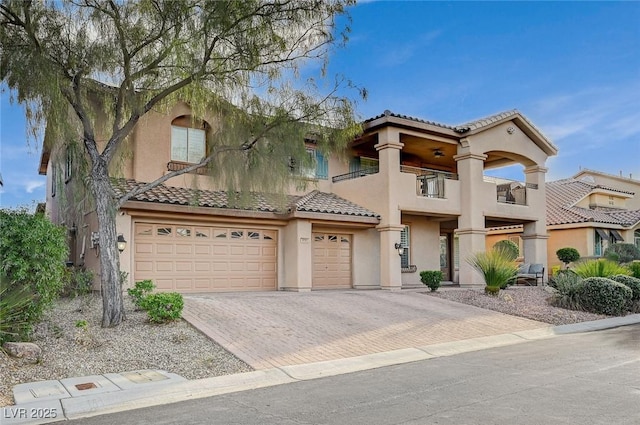 view of front of home with stucco siding, decorative driveway, an attached garage, a balcony, and a tiled roof