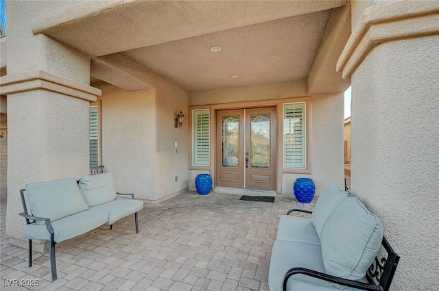 view of exterior entry with stucco siding, french doors, and a patio