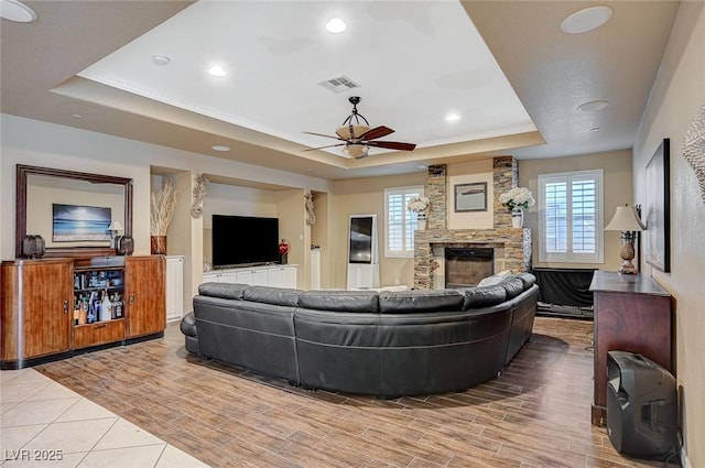 living area with a raised ceiling, plenty of natural light, a fireplace, and visible vents