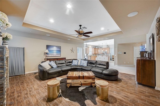 living room with a raised ceiling, wood finished floors, and baseboards