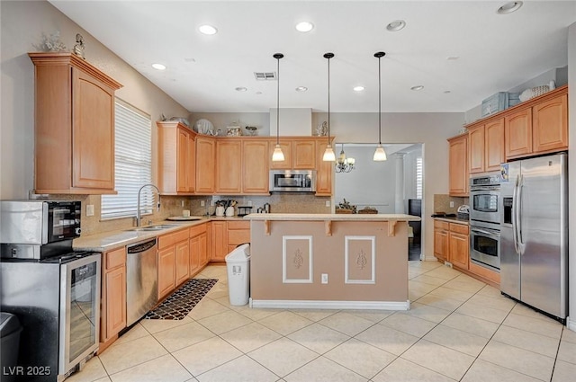 kitchen with visible vents, a kitchen island, light tile patterned flooring, stainless steel appliances, and a sink