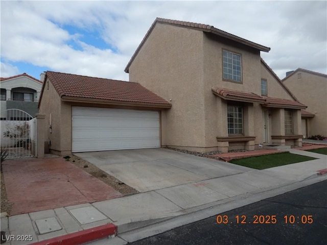 view of front of property featuring a tile roof, stucco siding, concrete driveway, and a gate