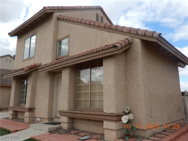 view of side of property featuring stucco siding and a tiled roof