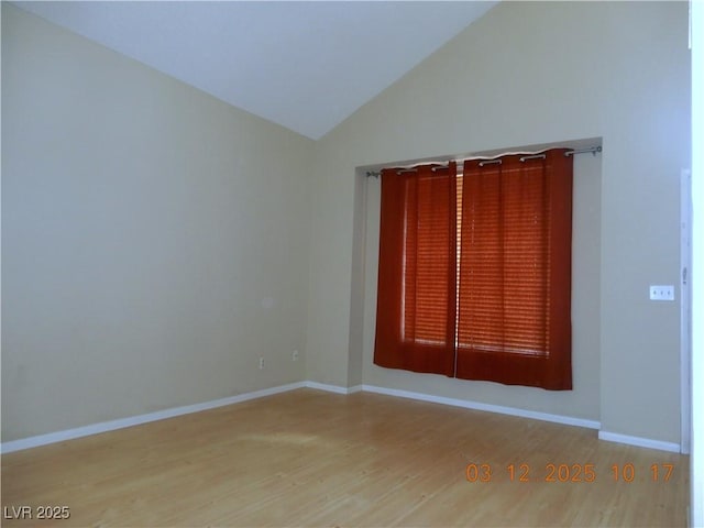 unfurnished room featuring vaulted ceiling, wood finished floors, and baseboards