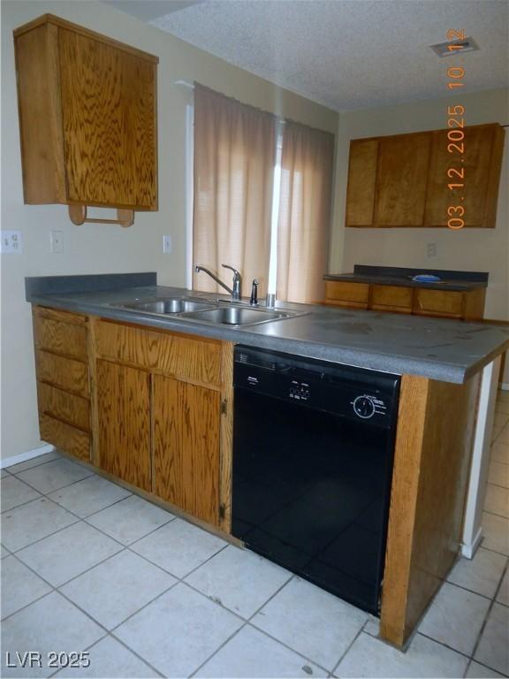 kitchen with dark countertops, brown cabinets, black dishwasher, and a sink