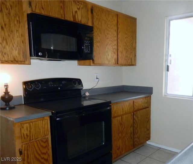 kitchen with black appliances, light tile patterned floors, brown cabinetry, and baseboards