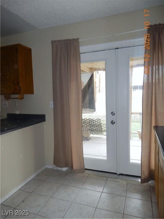 unfurnished dining area with french doors, a textured ceiling, a healthy amount of sunlight, and light tile patterned flooring