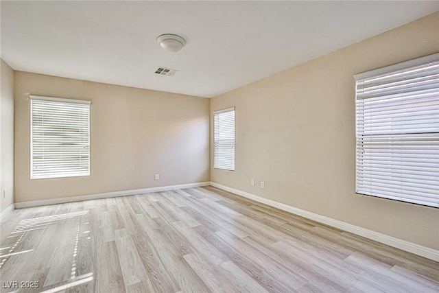 unfurnished room featuring visible vents, baseboards, and light wood finished floors