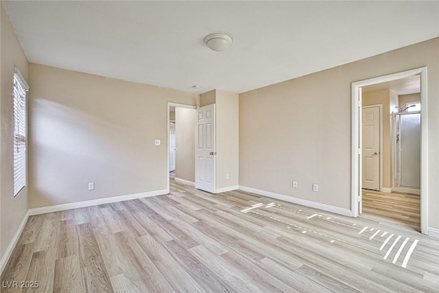 spare room with baseboards, light wood-style floors, and a healthy amount of sunlight