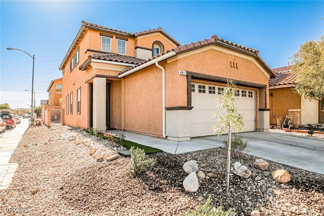 mediterranean / spanish-style home with a tile roof, an attached garage, driveway, and stucco siding