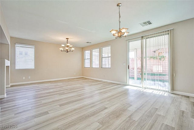 spare room with light wood-style flooring, baseboards, visible vents, and a chandelier