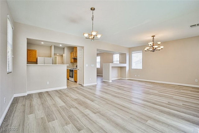 unfurnished living room featuring a notable chandelier, baseboards, visible vents, and light wood-type flooring