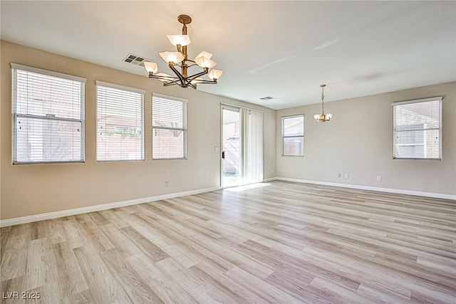 empty room featuring light wood-type flooring, visible vents, baseboards, and a chandelier