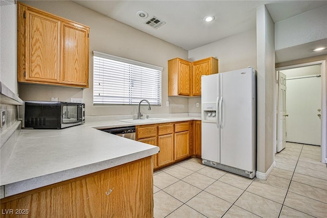 kitchen with light tile patterned floors, a sink, light countertops, white refrigerator with ice dispenser, and dishwasher