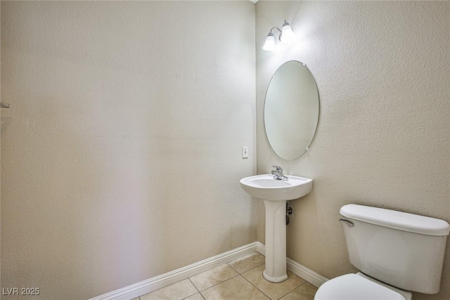 bathroom featuring tile patterned flooring, toilet, and baseboards