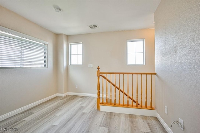 unfurnished room featuring visible vents, baseboards, and wood finished floors