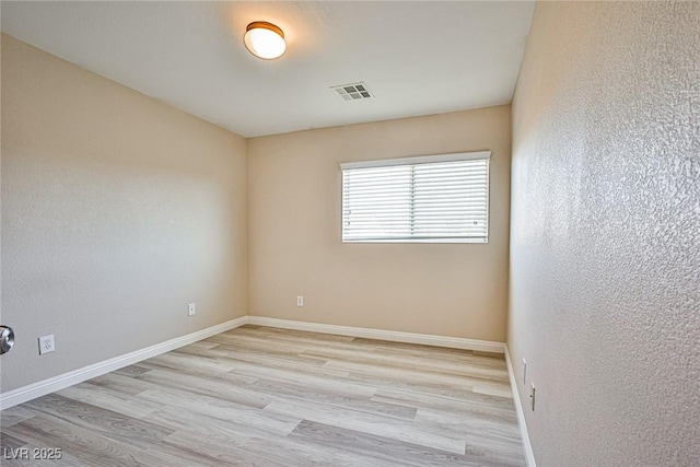 empty room with visible vents, baseboards, and wood finished floors