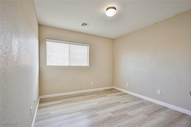 empty room with visible vents, baseboards, and wood finished floors